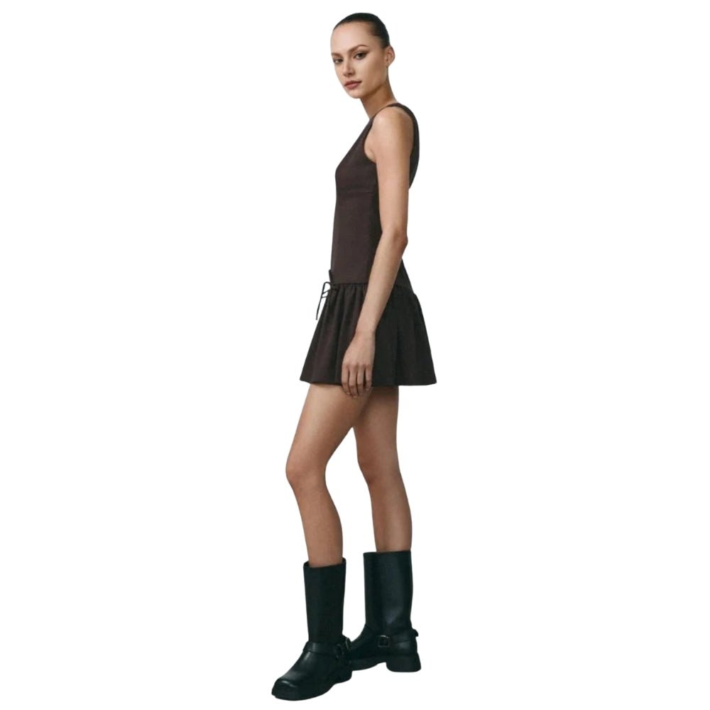 Woman wearing a Brown Kouvr dress and black boots on a white background