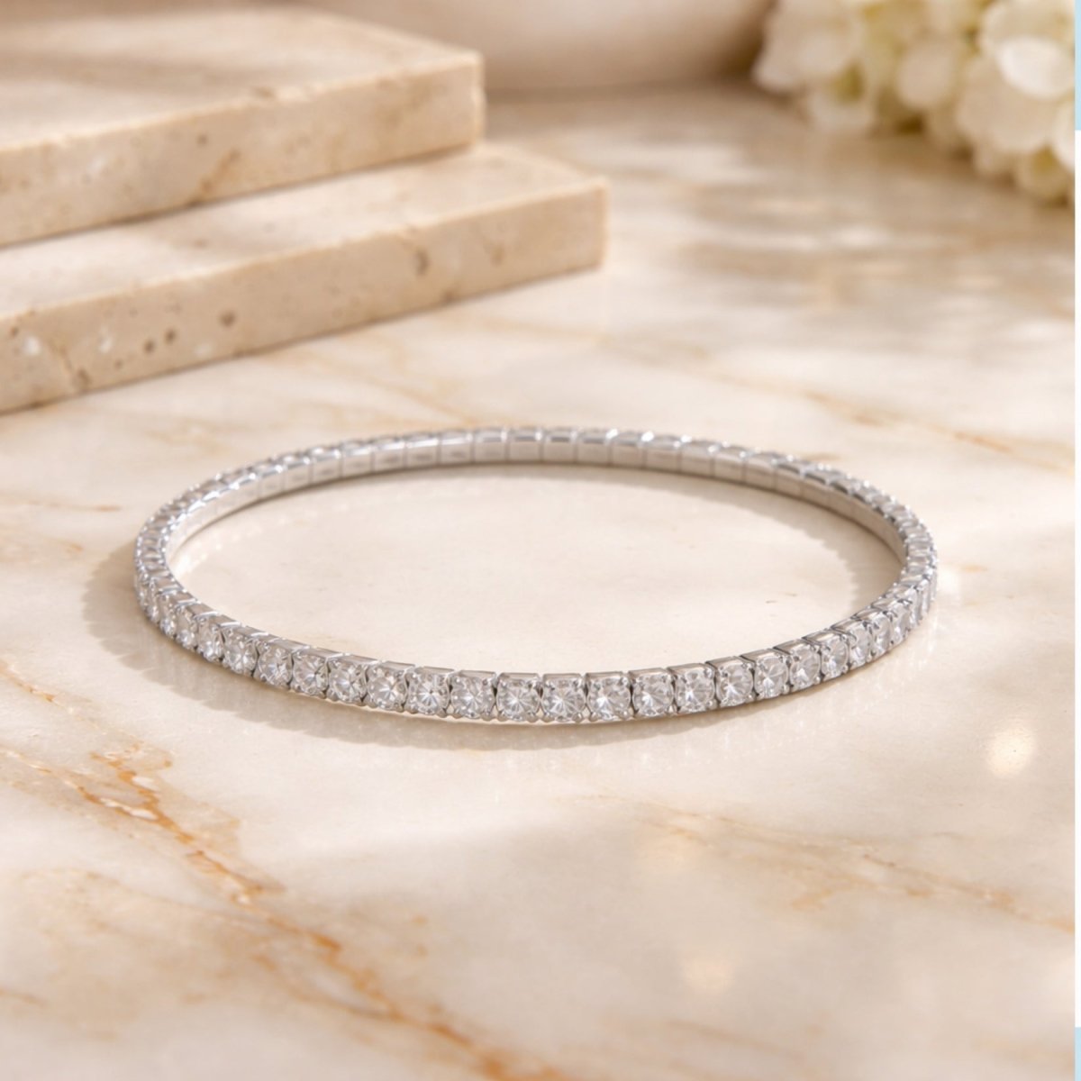 A bright, elegant shot of the Kouvr silver rhodium-plated stretch tennis bracelet on a marble surface.
