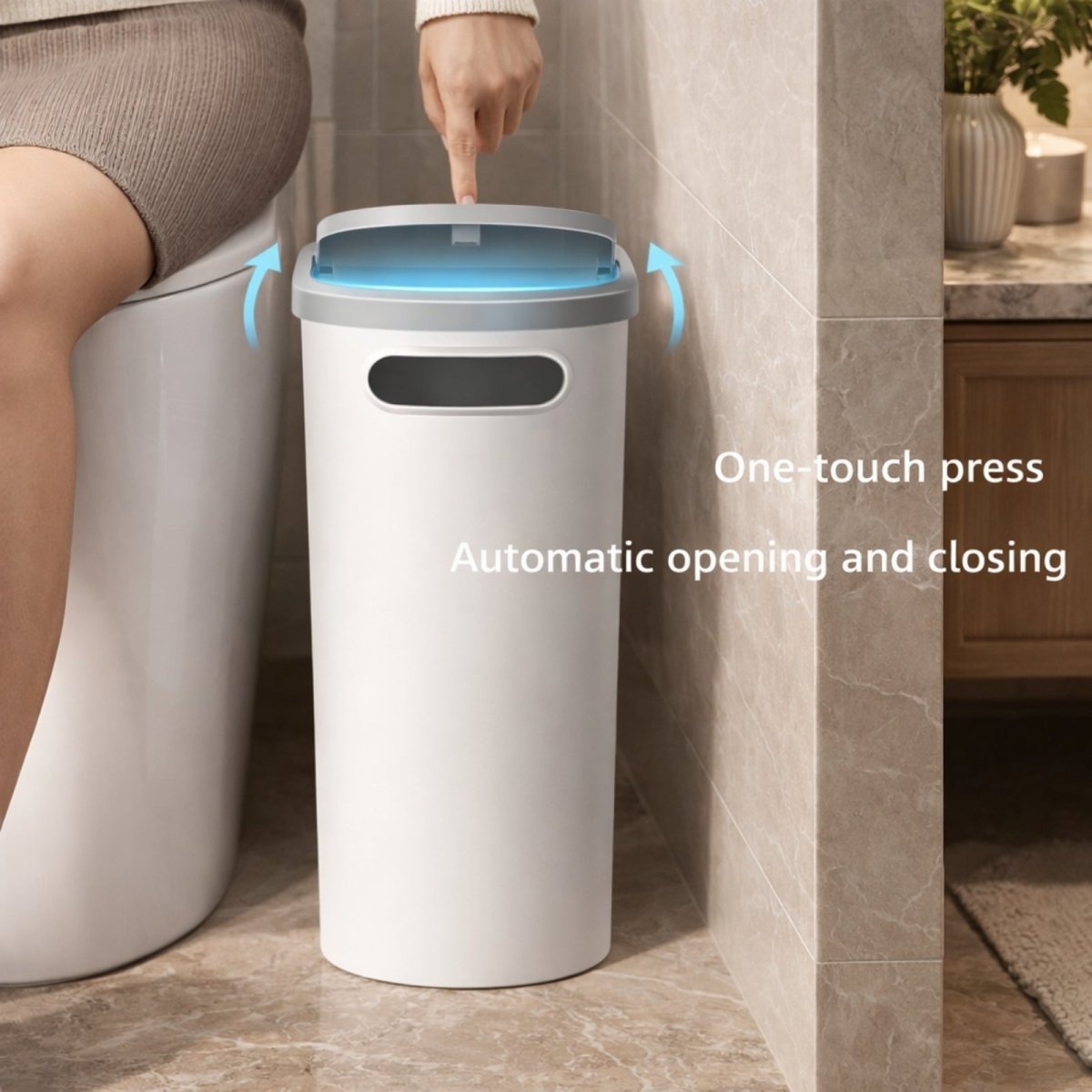 A woman's hand pressing the one-touch lid of the white and grey Kouvr slim trash can, positioned next to a toilet in a modern tiled bathroom.
