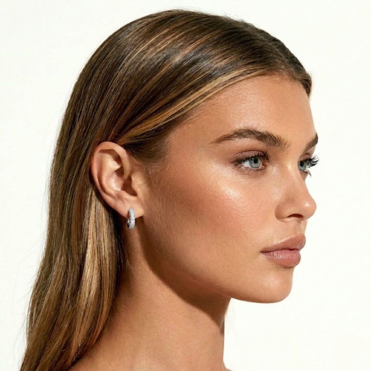 Side profile of a model showcasing how the Kouvr sterling silver pavé huggie earring sits snugly on the earlobe, highlighting its elegant design.