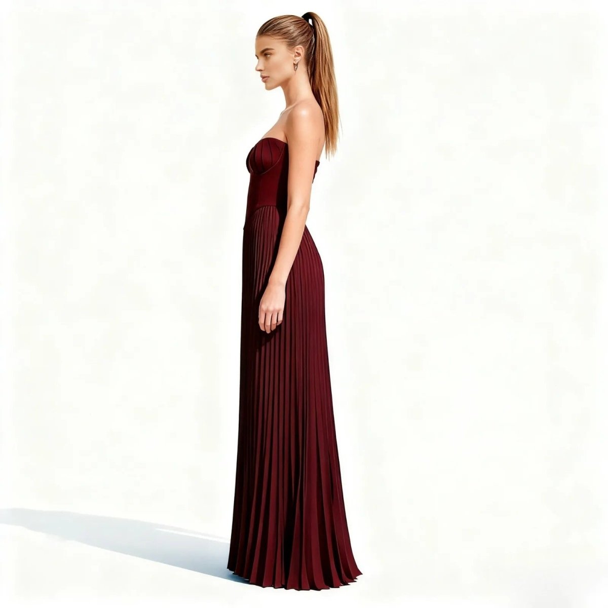 Woman wearing a burgundy kouvr pleated gown on a white background