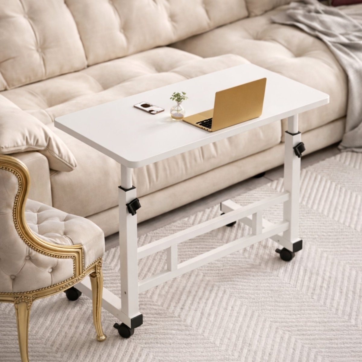 High-angle view of the Kouvr C-shaped side table with a laptop and phone, positioned next to a luxurious cream-colored sofa.