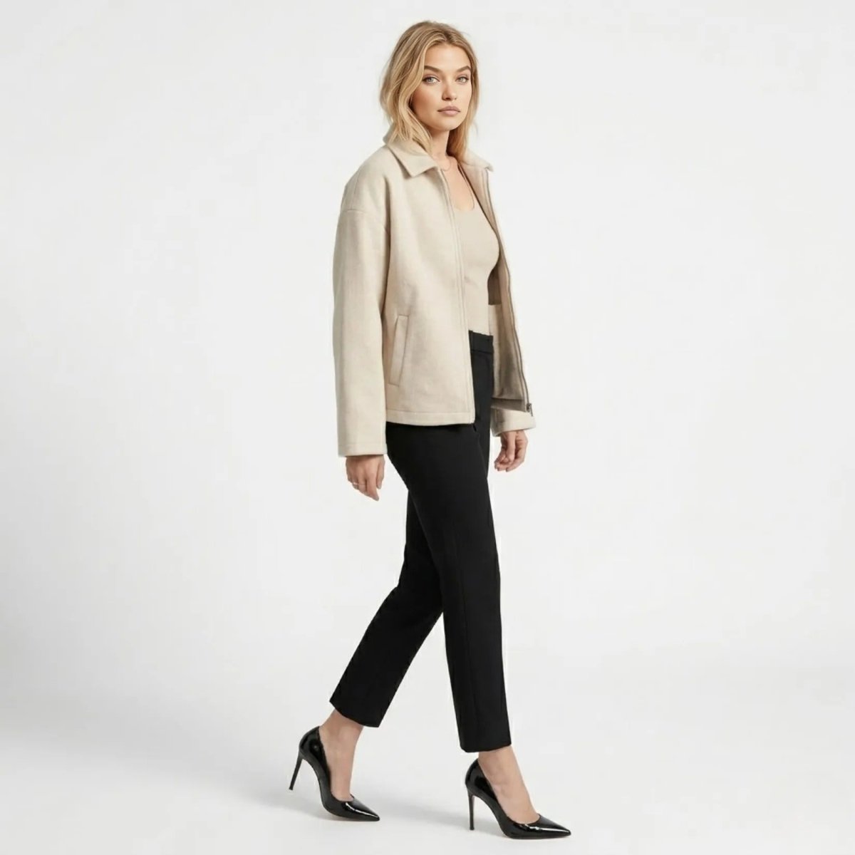 Side profile of woman walking confidently in the Kouvr minimalist white zip-up fall outerwear showcasing the relaxed fit