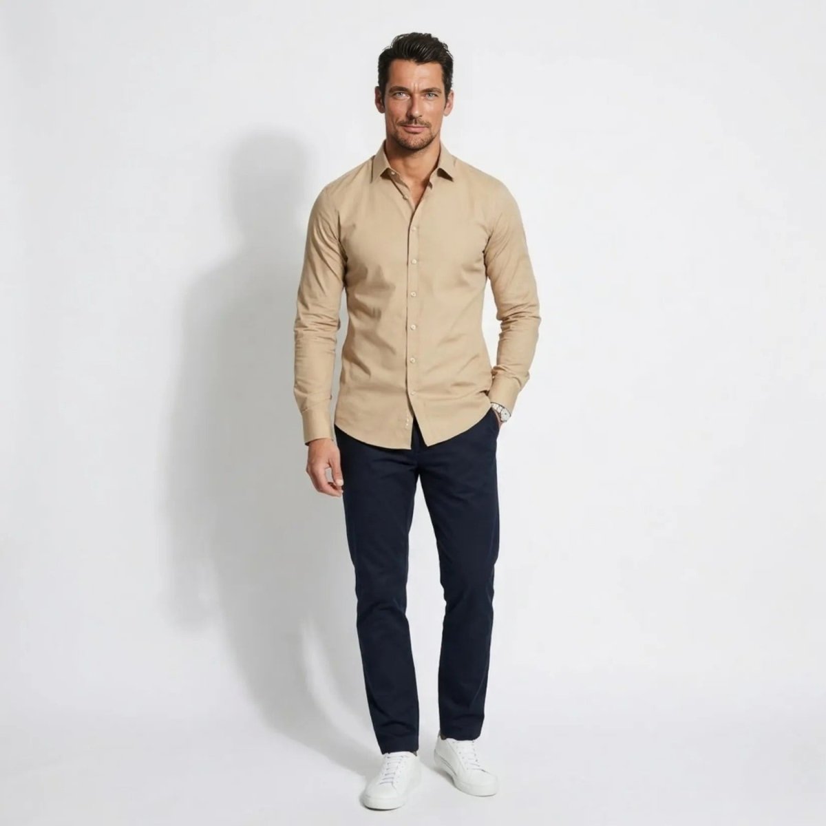 Front view of man wearing Kouvr premium khaki tailored fit long sleeve button down shirt with navy trousers and white sneakers.