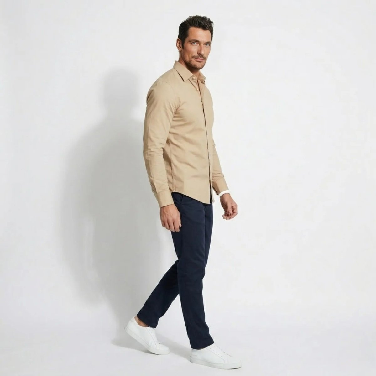 Side profile of male model walking wearing Kouvr khaki stretch cotton smart casual dress shirt untucked.