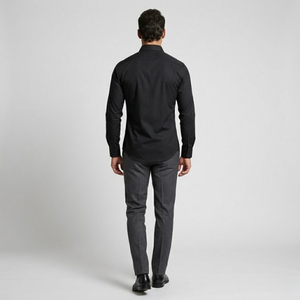 Back view of male model showcasing the fitted silhouette of the black stretch cotton dress shirt by Kouvr.
