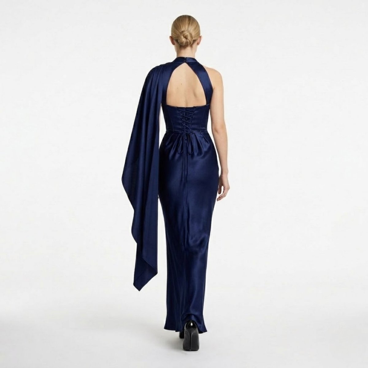 Back view highlighting the open back cutout and adjustable corset lace-up detail of the navy blue satin maxi gown.