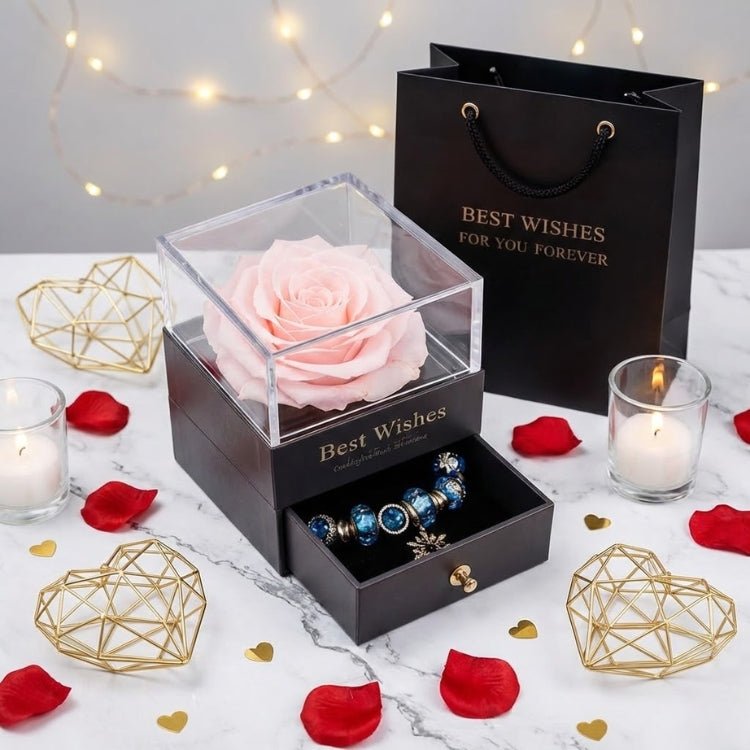A delicate pale pink forever rose in a luxury gift box, displayed with a "Best Wishes" gift bag and candles.