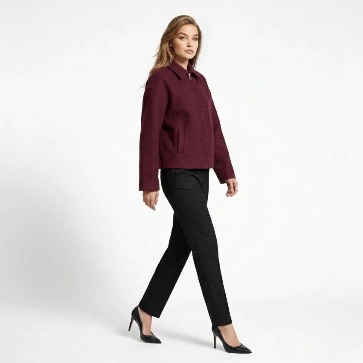 Side profile of woman walking in Kouvr wine red boxy wool jacket and black heels