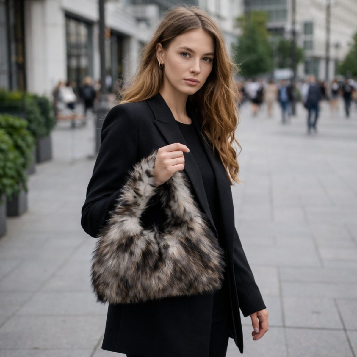 A model in a chic all-black blazer and pants outfit accentuating the Kouvr Linnea Wolf faux fur purse.
